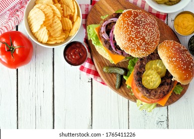 BBQ Hamburgers With Potato Chips. Overhead View Table Scene On A White Wood Background.