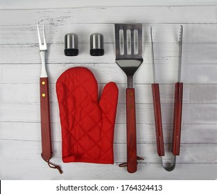 BBQ Instruments Kit (tongs, Glove, Knife, Fork, Spatula, Peper And Salt Shakers) Close Up Isolated On White Wooden Background Flat Lay