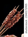 BBQ meat skewers, pork and lamb, charcoal fire and smoke, dark background, food for camping and parties