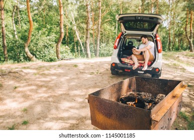 Bbq On Fire. Man Sitting In Car Trunk. Car Travel Concept