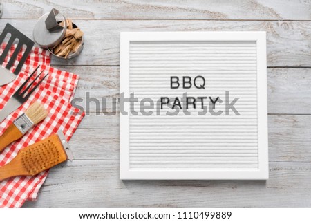 BBQ Party sign with BBQ cooking tools on a wood background.