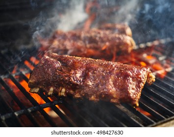 bbq pork ribs cooking on flaming grill shot with selective focus