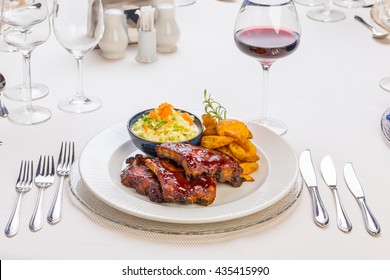 Bbq Pork Ribs With Potatoes And Salad,  On A Classy Restaurant Table