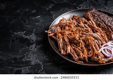 BBQ pulled pork meat on plate. Black background. Top view. Copy space.