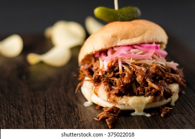 BBQ Pulled Pork Sandwich.
Slow cooked pulled pork with BBQ sauce, pickled onions, coleslaw and cheese served in a hamburger bun with dill pickle and some chips as sides. Perfect for lunch or dinner!