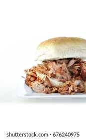 BBQ pulled pork in a soft bread roll shot against a white background with generous accommodation for copy space.