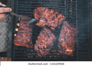 BBQ Ribs And Tri-tip Meat Ready To Smoke And Cook Over A Hot Charcoal Grill. Using Wood Chips For Smoky Flavor And Brush To Add BBQ Sauce On Top Of The Seasoning. Slices Of Meat Ready To Eat