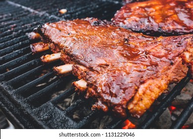 BBQ Ribs And Tri-tip Meat Ready To Smoke And Cook Over A Hot Charcoal Grill. Using Wood Chips For Smoky Flavor And Brush To Add BBQ Sauce On Top Of The Seasoning. Slices Of Meat Ready To Eat