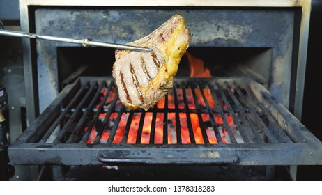 Bbq Sauce On Beef On A Grill Outdoors Steak. Close Up Shot Of Flame Grilled BBQ T Bone Beef Steak. Flames Slowly Rise Through A Barbeque Grill And Sear