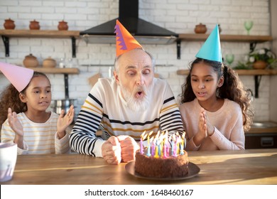 Bday Cake. Bearded Man In A Birthday Hat Blowing Down The Candles On His Bday Cake