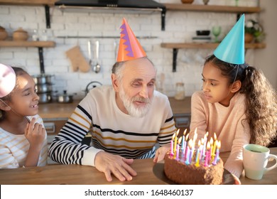 Bday Party. Bearded Man In A Birthday Hat Having His Birthday With His Granddaughters