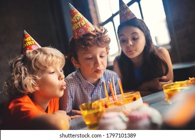 Bday wish. Three kids sitting at the table and blowing out the canldes