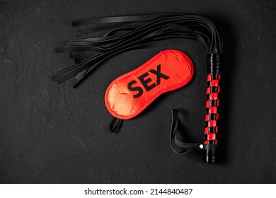 BDSM, Bondage Play, Fetish Wear And Kinky Sex Toy Concept With Close Up On Erotic Mask And Red Handcuffs Isolated On Black Silk Background