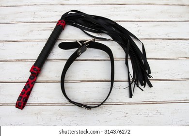 BDSM Toy, A black and red BDSM toy, a whip and collar over a distressed wood background