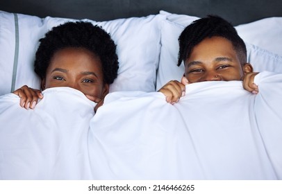 Be back later, going back to bed. Shot of a young couple hiding under the covers in bed at home.