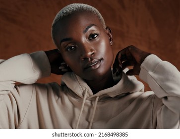 Be Bold, Because Youre Beautiful. Studio Portrait Of An Attractive Young Woman Wearing A Hoodie And Posing Against A Brown Background.