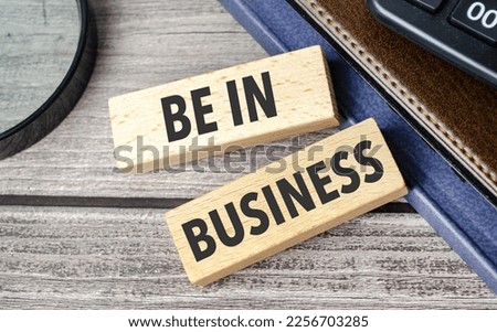 be in business. text on wooden blocks on wooden background with office supplies