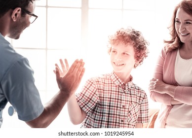 Be Careful. Healthy Smiling Kid Giving A High Five To His Friendly Doctor After Getting Better And Treating At A Hospital.