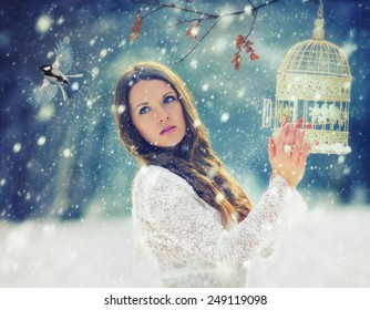 Be free / Young woman release a bird from a cage in the snowfall