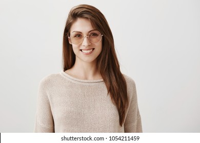 Be on trendy side. Portrait of beautiful young caucasian woman in stylish round sunglasses smiling joyfully, walking along street with friends, enjoying sunny days in spring. Advertisement concept