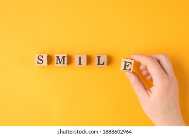 Be positive and smile concept. Pov close up flat lay view photo of female hand holding wooden block building word smile isolated vivid color backdrop
