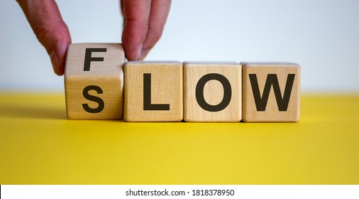 Be slow or in the flow. Male hand turns a cube and changes the word 'slow' to 'flow'. Beautiful yellow table, white background, copy space. Business concept.