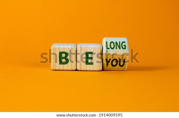 Be you, belong symbol.\
Turned a cube and changed words \'be you\' to \'belong\'. Beautiful\
orange background. Business, belonging and be you belong concept.\
Copy space.