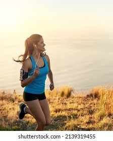 Be Your Personal Best. Cropped Shot Of A Young Woman Listening To Music While Out For A Run.