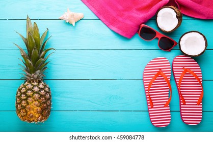 Beach accessories, coconuts and pineapple on blue wooden background. Top view and copy space
