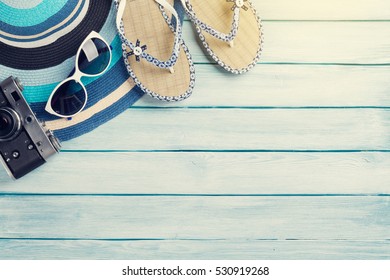 Beach accessories. Flip flops, camera, hat and sunglasses on wooden background. Top view with copy space. With sun toned - Powered by Shutterstock