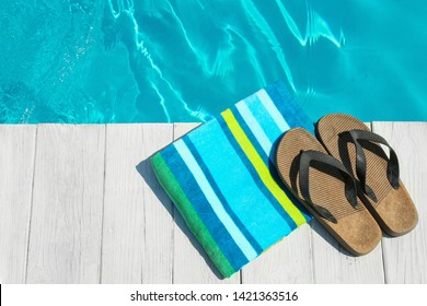 Beach accessories on wooden deck near swimming pool, top view. Space for text