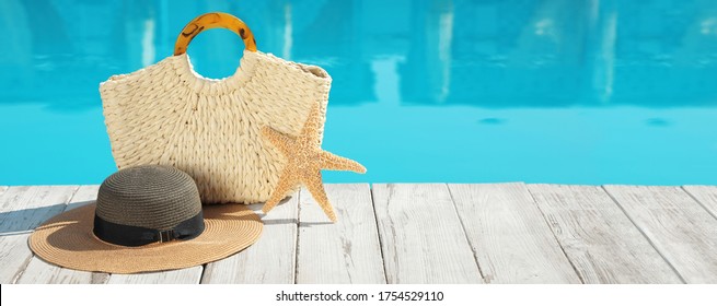 Beach accessories on wooden deck near outdoor swimming pool, space for text. Banner design
