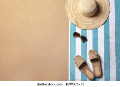 Beach accessories and space for text on sand, top view. Summer vacation