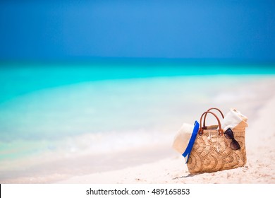 Beach accessories - straw bag, headphones, toy plane and sunglasses on the beach - Powered by Shutterstock