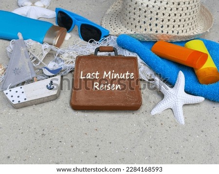 Beach accessories with the text Last Minute Travel on a suitcase. German inscription means last minute travel.
