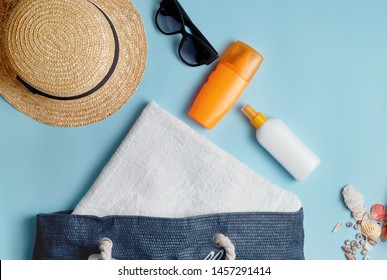 Beach Bag With Beach Accessories On A Colored Background Top View. Sunscreen, Towel, Glasses, Hat.