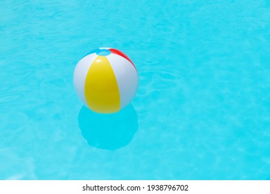 Beach Ball Floating On Water Surface Of A Swimming Pool. Summer Background. Copy Space