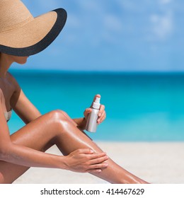 Beach Body Suntan Skin Care Travel Vacation. Bikini Hat Woman Applying Sunscreen Lotion Putting Cream On Tanned Sexy Legs Sunbathing Sun Tanning Sitting On Sand With Turquoise Blue Ocean Background.