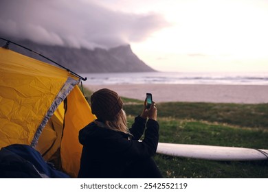 Beach, camping and woman with picture, ocean and capture moment with adventure. Person, seaside and surfer with smartphone, campsite and getaway trip with travel vlogger, photography and vacation - Powered by Shutterstock