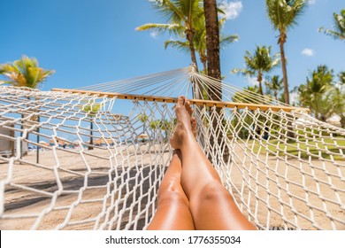 Beach Caribbean travel holiday vacation woman feet selfie lying down relaxing on hammock oustside sunbathing. Girl relaxing taking pov photo of her legs sun tanning in tropical summer destination.