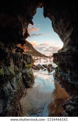 Beach cave with tidal flows and a window to a pretty sunrise