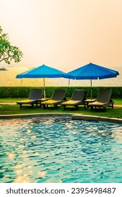 beach chair or pool bed with umbrella around swimming pool with sunset and sea background - Shutterstock ID 2395498487
