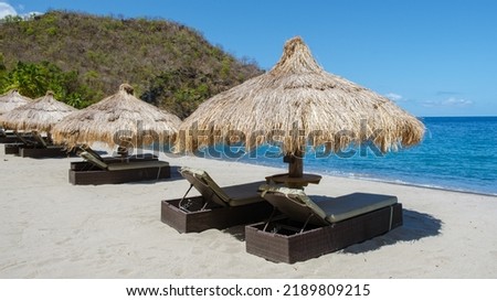Beach chairs and umbrellas on a tropical beach in St Lucia, white beach with palm trees in Saint Lucia Caribbean. The beautiful White sandy beach of Caribbean Gros, umbrellas with chairs