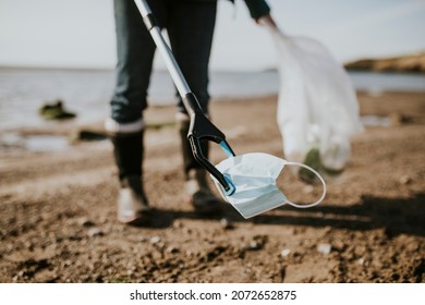 Beach Cleanup Volunteer Picking Up Face Mask For Environment Campaign