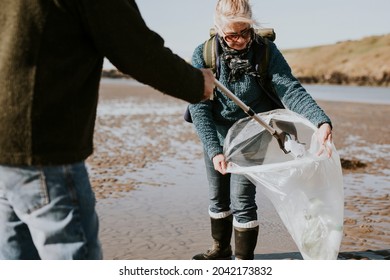 Beach cleanup volunteers picking up trash for environment campaign - Powered by Shutterstock