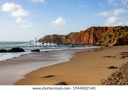 Beach with clear water and red cliffs in Algarve, Portugal