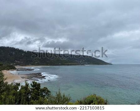 Beach coast line with sand and rolling hills on Great ocean road Australia Victoria with overcast dark rainy clouds