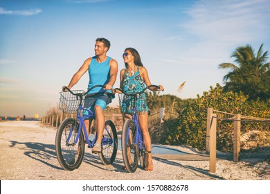 Beach couple biking enjoying leisure sport recreational activity relaxing outdoors at sunset. Young woman and man riding bicycles on USA Florida vacation. Summer people lifestyle happy. - Powered by Shutterstock