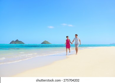 Beach Couple Happy Having Fun On Hawaii Honeymoon. Romantic Couple Cheerful And Full Of Happiness On Travel Vacation, Lanikai Beach, Oahu, Hawaii, USA With Mokulua Islands. Asian Woman, Caucasian Man