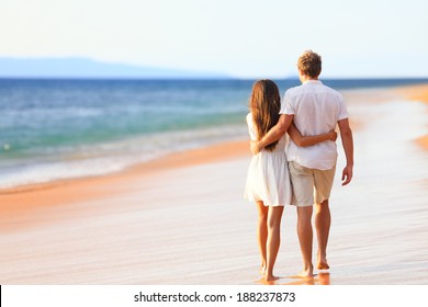 Beach Couple Walking On Romantic Travel Honeymoon Vacation Summer Holidays Romance. Back Rear View Of Casual Young Happy Lovers In Full Body Length On Beach.